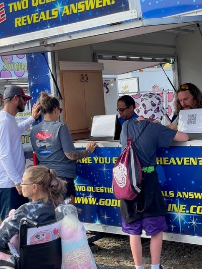 People visit a fair booth that reads, "Are you going to heaven?"
